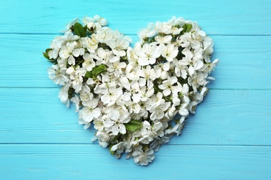 Heart made of beautiful fresh spring flowers on color background, top view