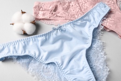 Women's underwear and cotton flower on light grey background, closeup