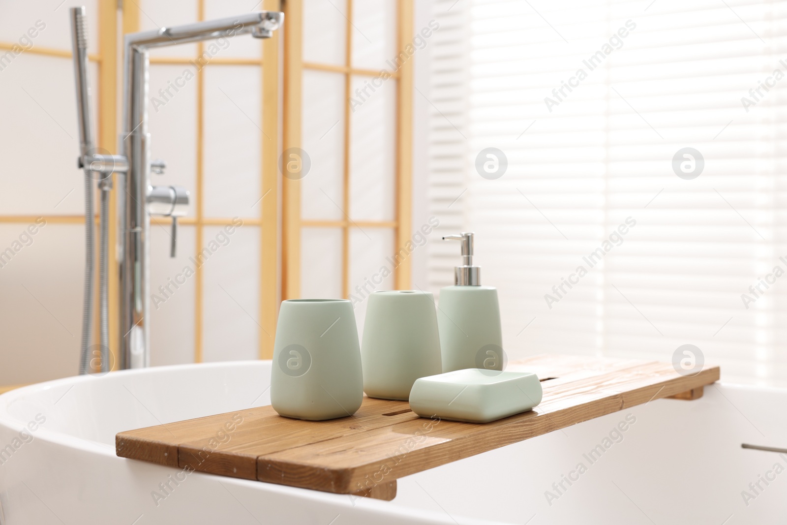 Photo of Set of bath accessories on tub in bathroom