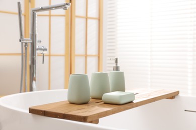 Photo of Set of bath accessories on tub in bathroom