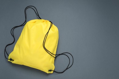 Photo of Yellow drawstring bag on grey background, top view. Space for text