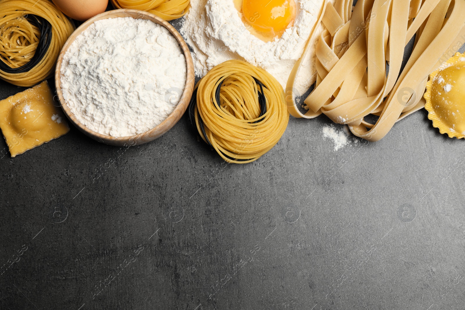 Photo of Flat lay composition with different types of pasta on grey table. Space for text