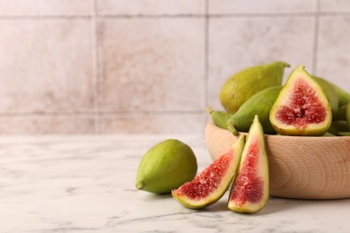 Cut and whole green figs on white marble table, space for text