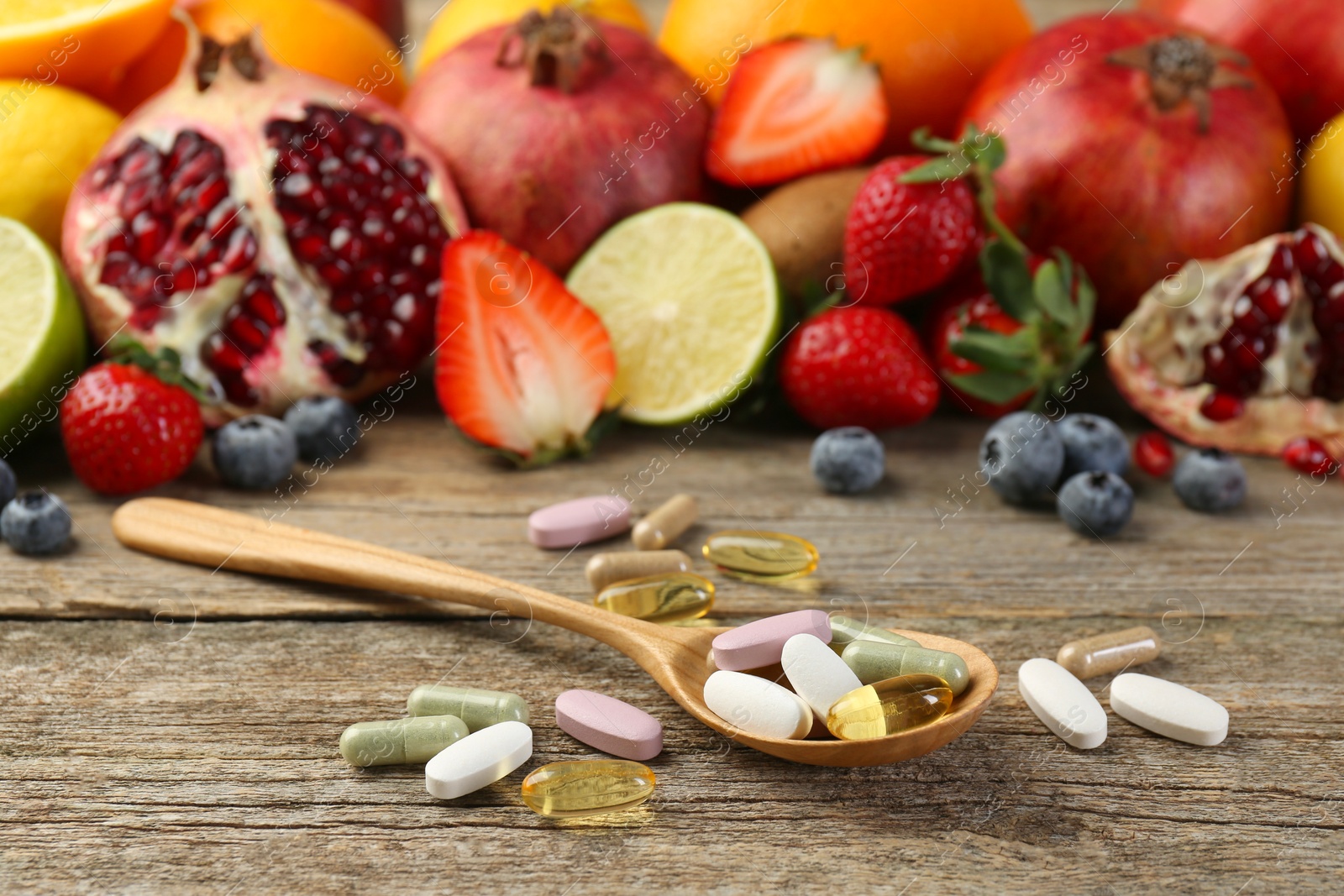 Photo of Different vitamin pills and fresh fruits on wooden table