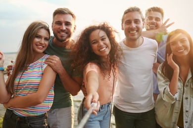 Happy young people taking selfie outdoors on sunny day