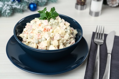 Photo of Traditional russian salad Olivier served on white wooden table