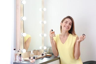 Photo of Woman applying perfume near mirror in dressing room