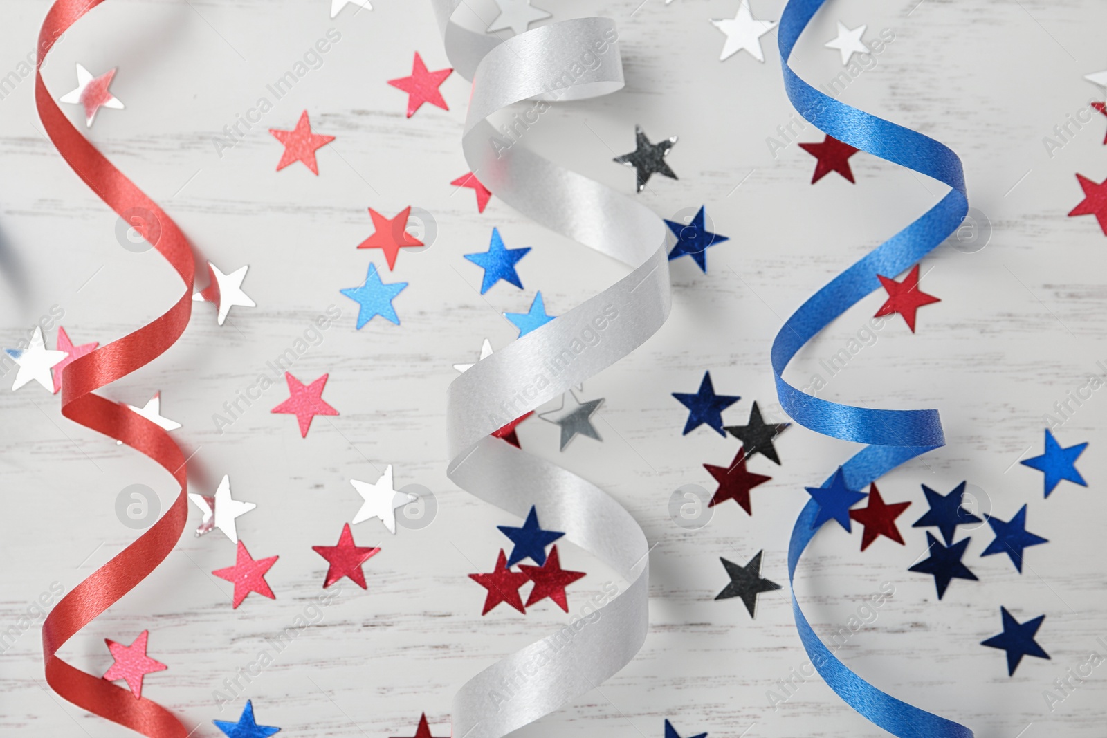 Photo of Flat lay composition with colorful party streamers on wooden table. USA Independence Day