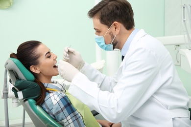 Photo of Professional dentist working with patient in modern clinic