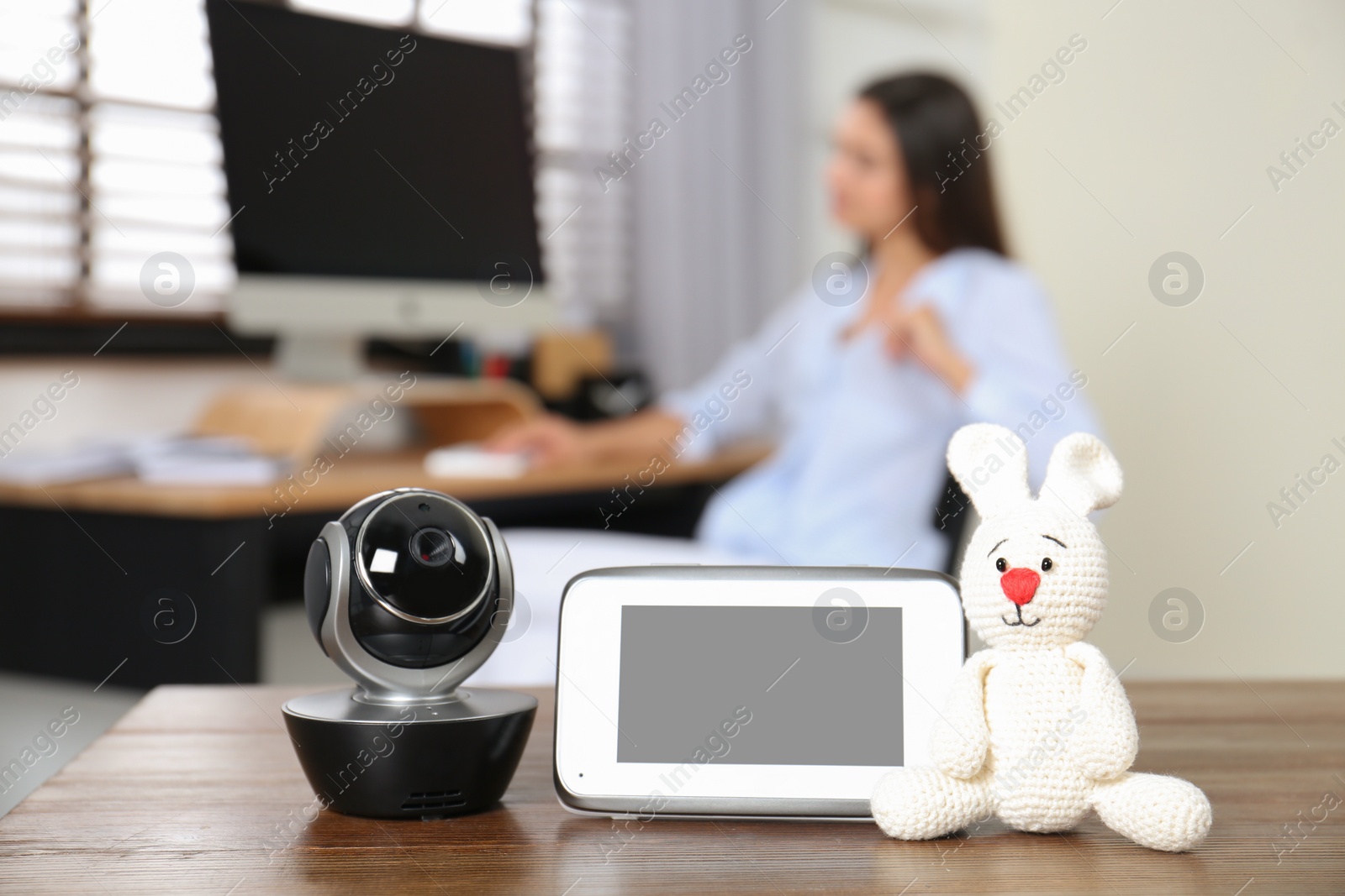 Photo of Baby monitor, camera with toy on table and woman working in home office. Video nanny
