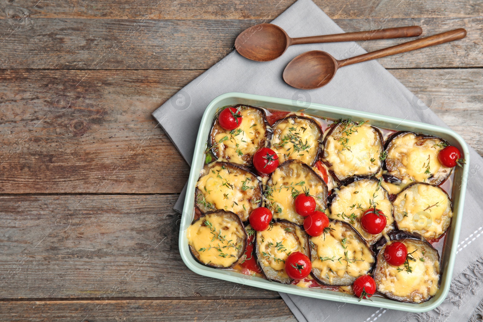 Photo of Flat lay composition with baked eggplant, tomatoes and cheese in dishware on wooden table. Space for text