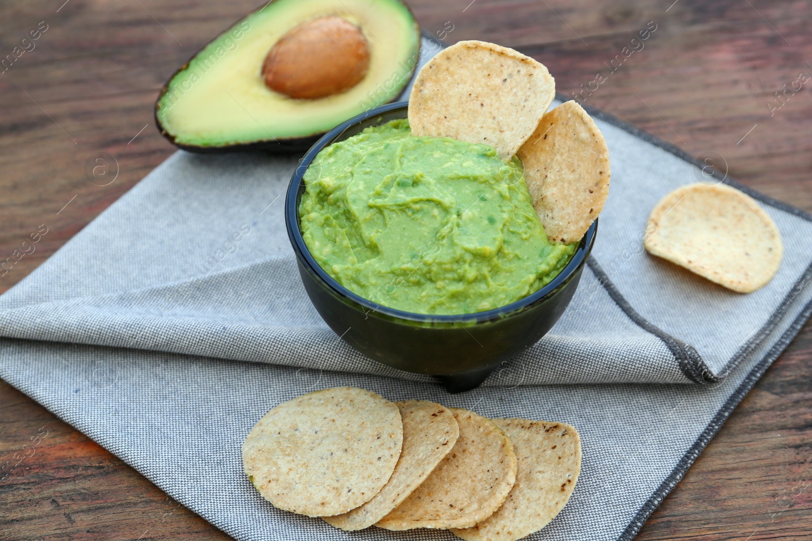 Photo of Delicious guacamole made of avocados with nachos on wooden table