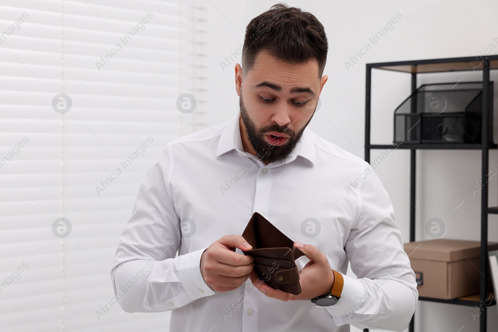 Photo of Confused man with empty wallet in office