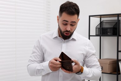 Confused man with empty wallet in office