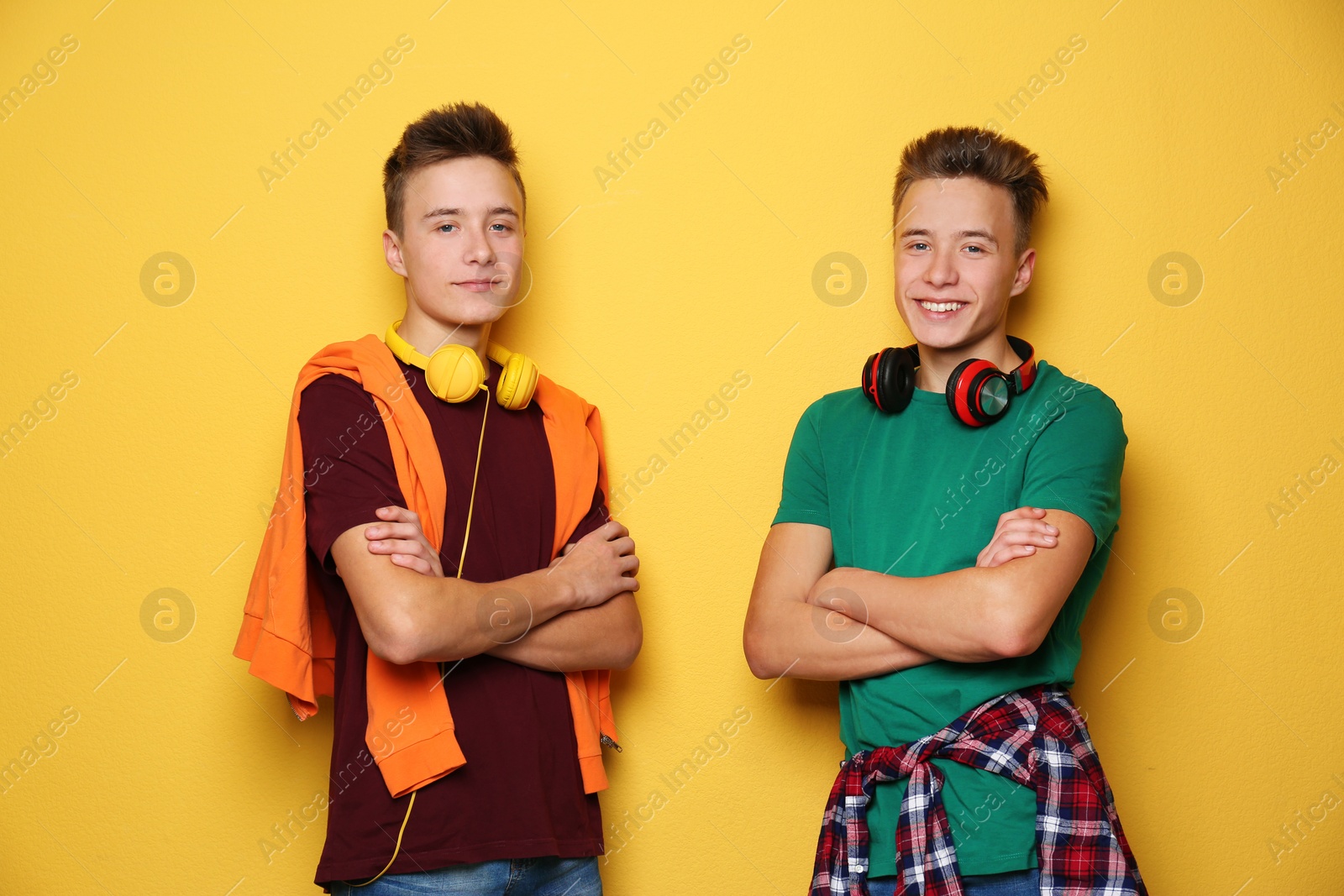 Photo of Teenage twin brothers with headphones on color background