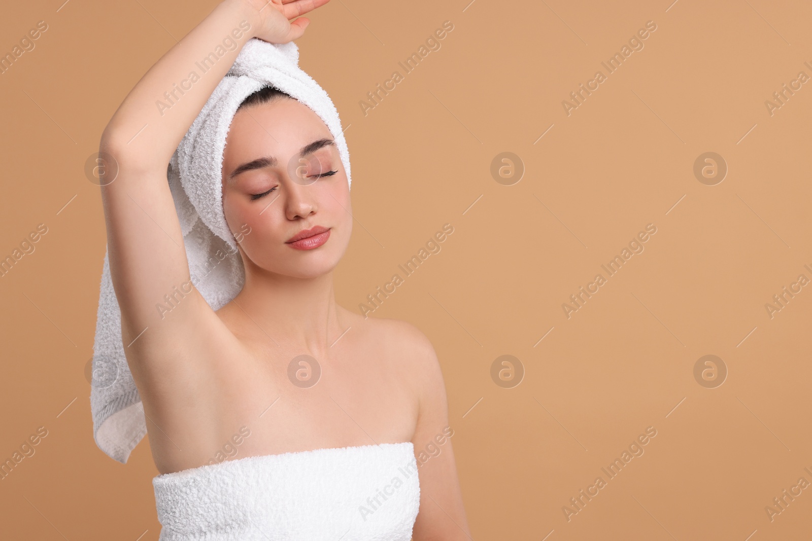 Photo of Beautiful woman showing armpit with smooth clean skin on beige background, space for text