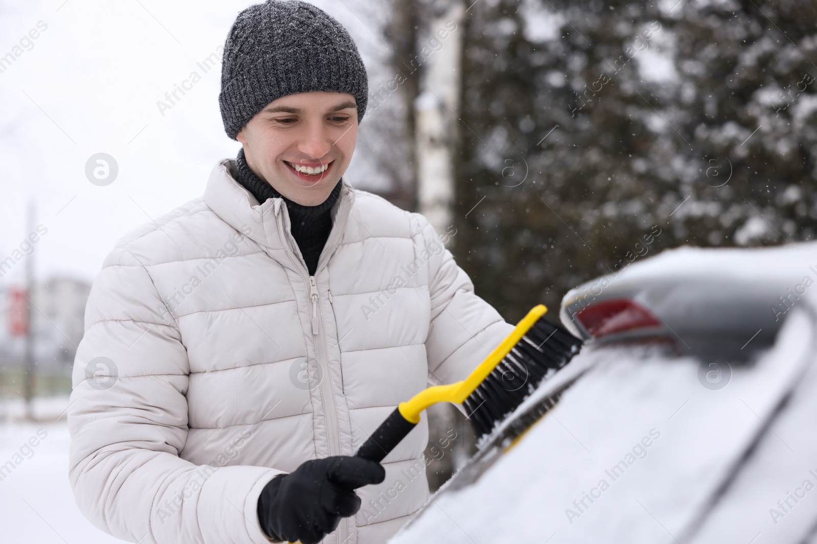 Photo of Man cleaning snow from car window outdoors