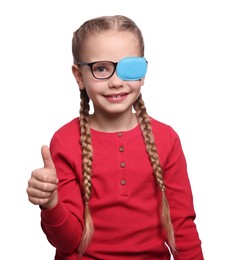 Photo of Happy girl with eye patch on glasses showing thumb up against white background. Strabismus treatment