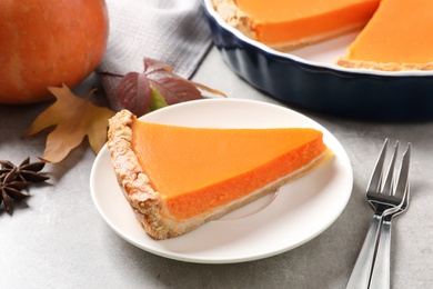 Photo of Plate with piece of fresh delicious homemade pumpkin pie on gray table