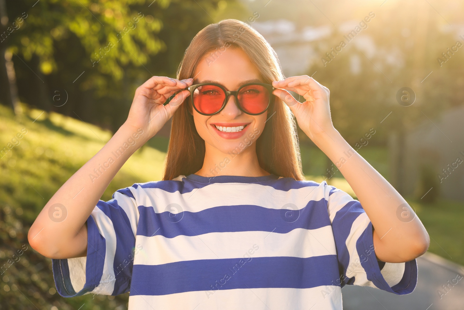 Photo of Beautiful smiling woman wearing sunglasses in park