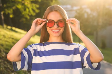 Beautiful smiling woman wearing sunglasses in park