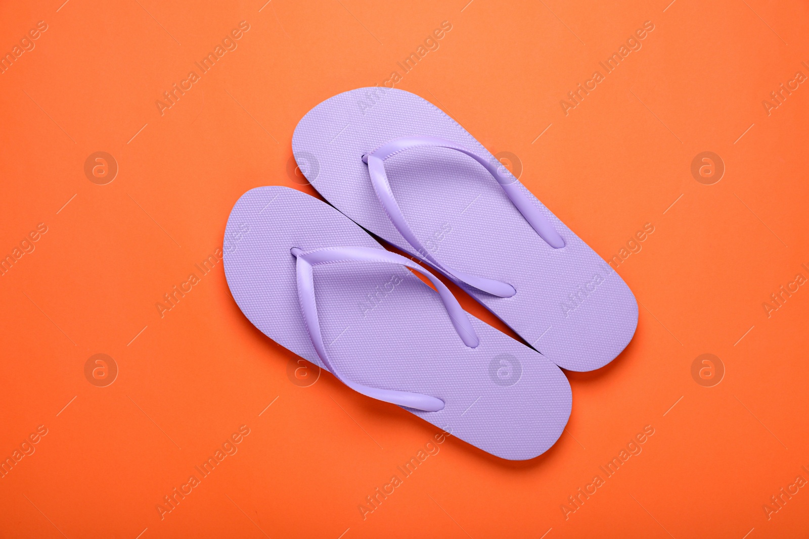 Photo of Stylish violet flip flops on orange background, top view