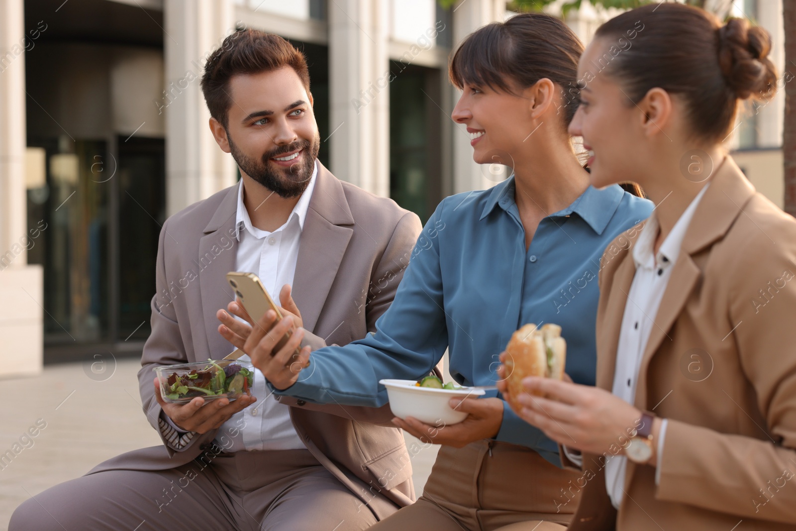 Photo of Business lunch. Happy colleagues spending time together during break outdoors