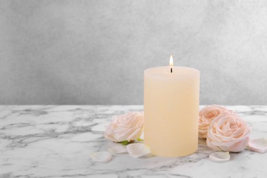Photo of Spa composition with burning candle and flowers on white marble table, space for text