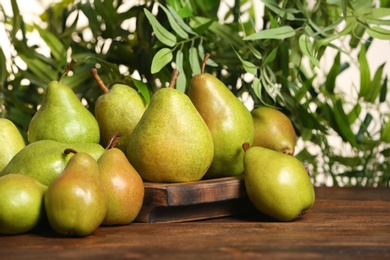 Photo of Fresh ripe pears on wooden table against blurred background