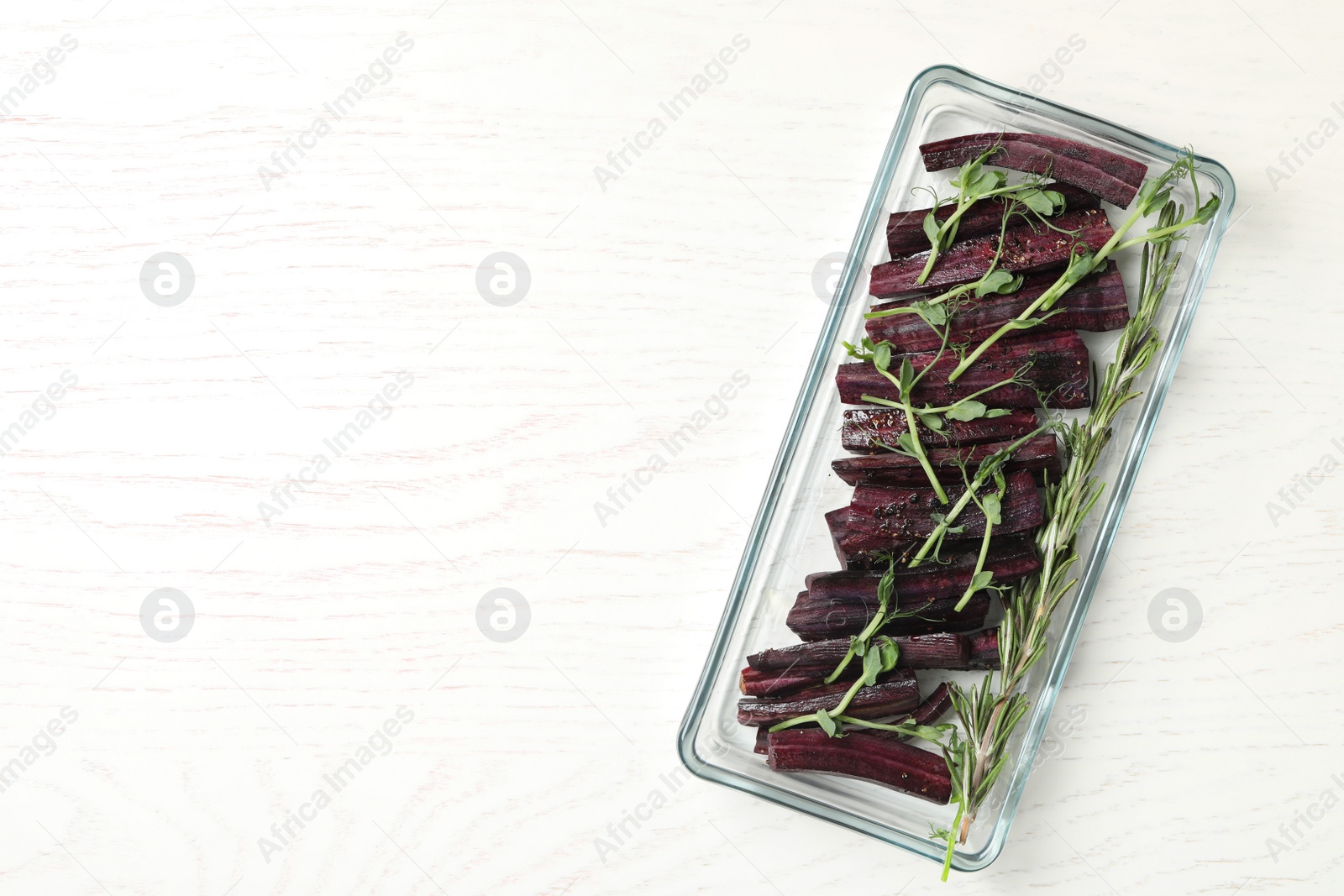 Photo of Raw black carrot in baking dish on white wooden table, top view. Space for text