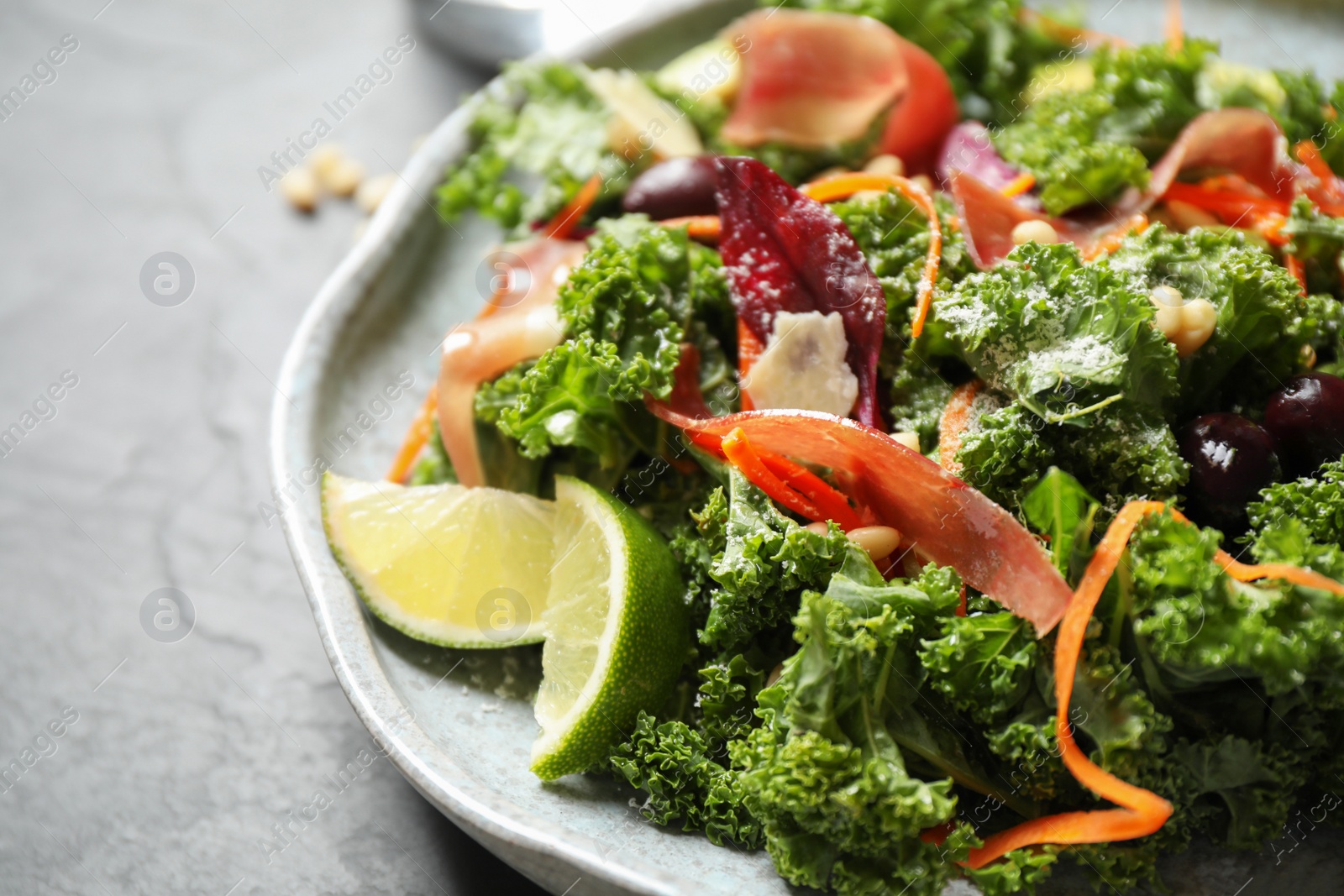 Photo of Tasty fresh kale salad on grey table, closeup