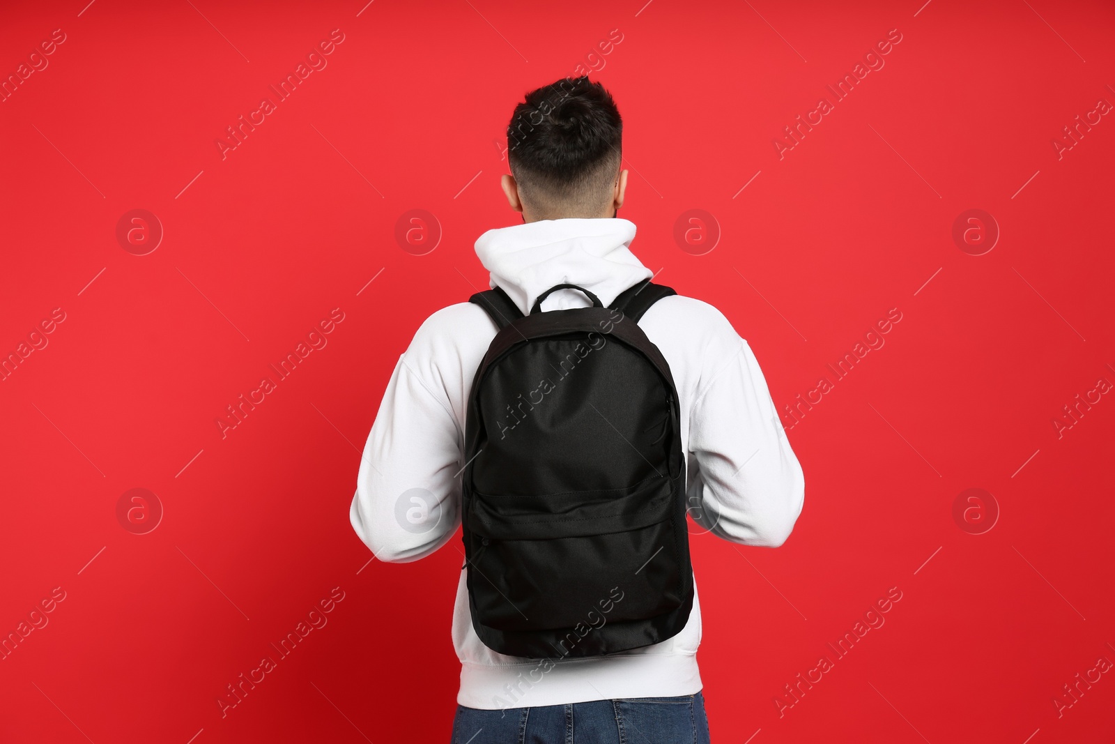 Photo of Young man with stylish backpack on red background, back view