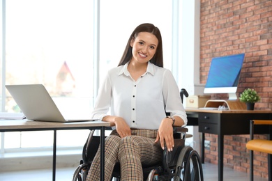 Portrait of young woman in wheelchair at workplace