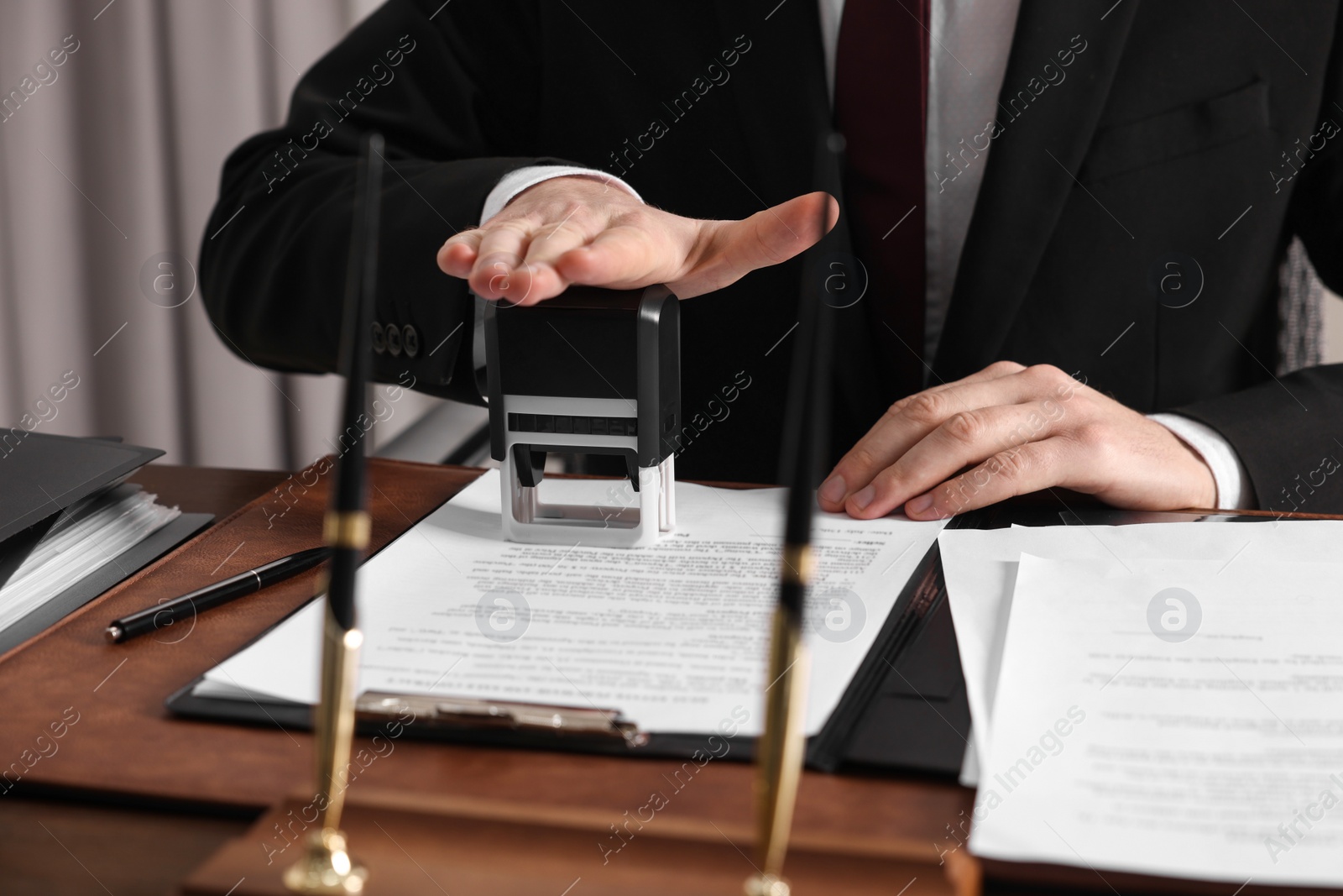 Photo of Notary stamping document at table in office, closeup