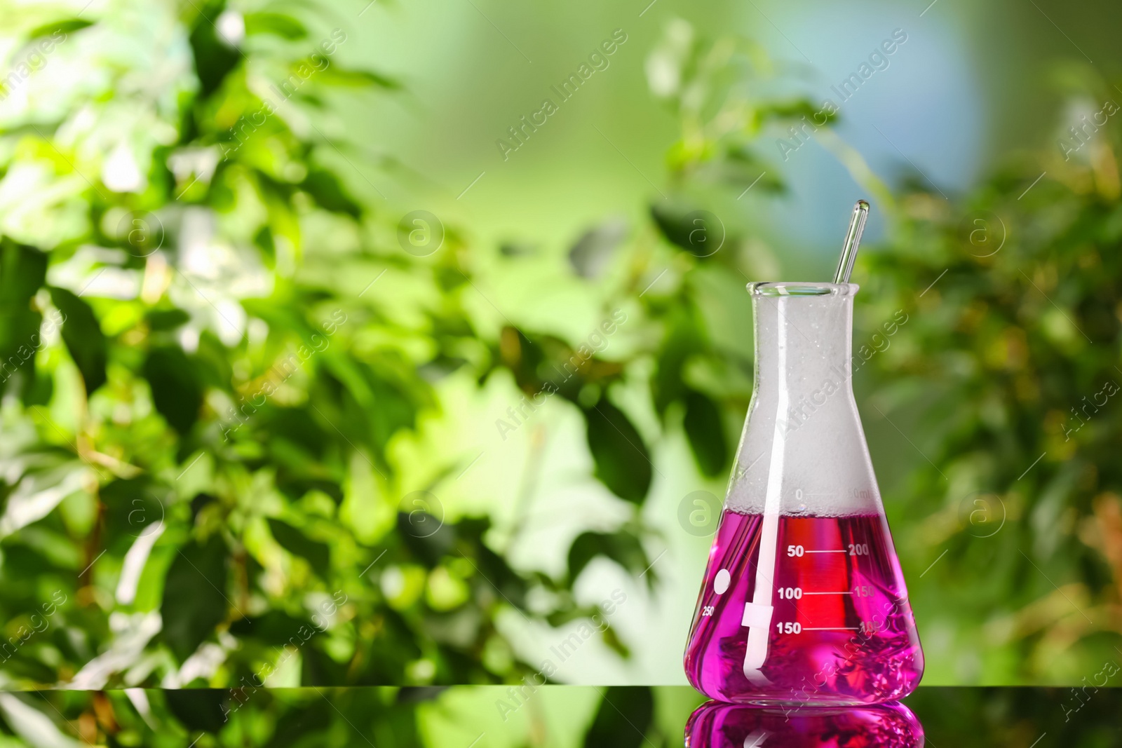 Photo of Laboratory flask with colorful liquid on glass table outdoors, space for text. Chemical reaction