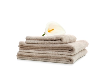 Stack of clean folded towels with flower on white background