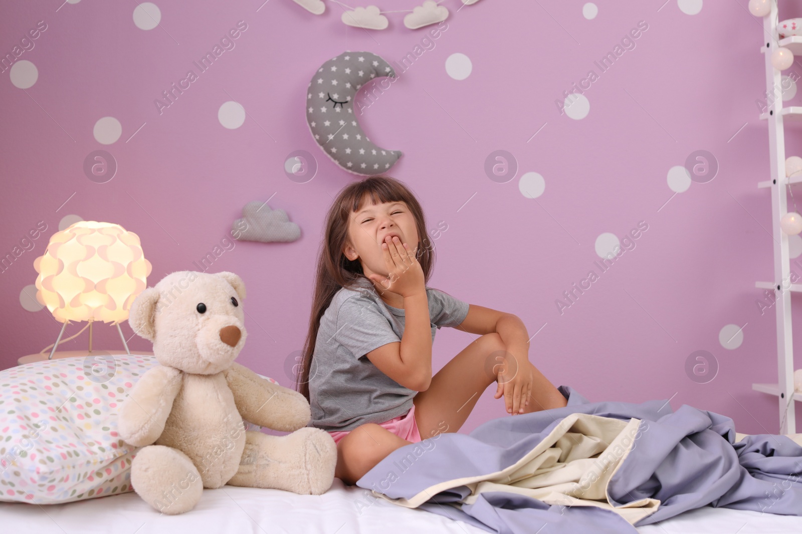 Photo of Little girl yawning on bed at home. Time to sleep