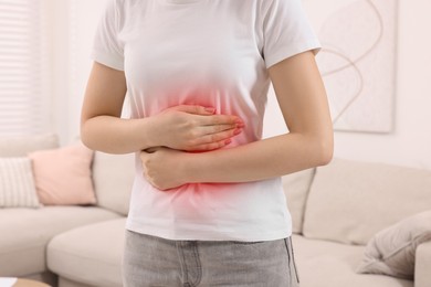 Woman suffering from abdominal pain at home, closeup