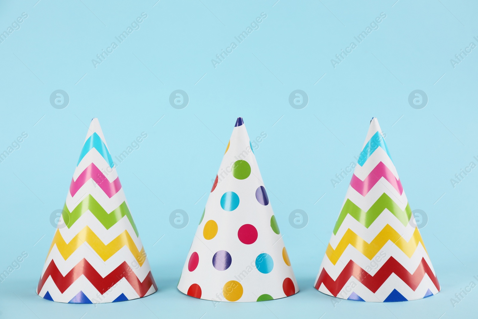 Photo of Bright party hats on light blue background