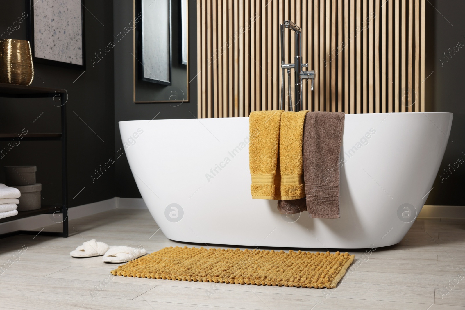 Photo of Stylish bathroom interior with bath tub and soft yellow mat