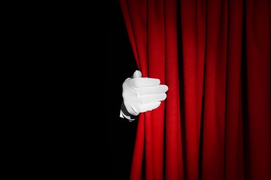 Photo of Person opening red front curtains on black background, closeup. Space for text