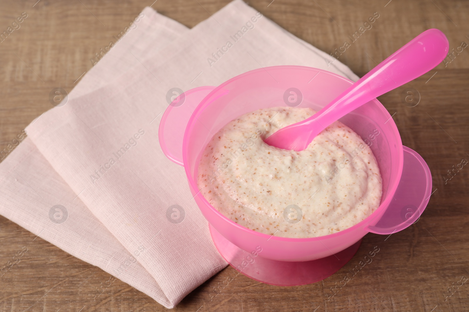 Photo of Baby food. Puree and spoon in bowl on wooden table