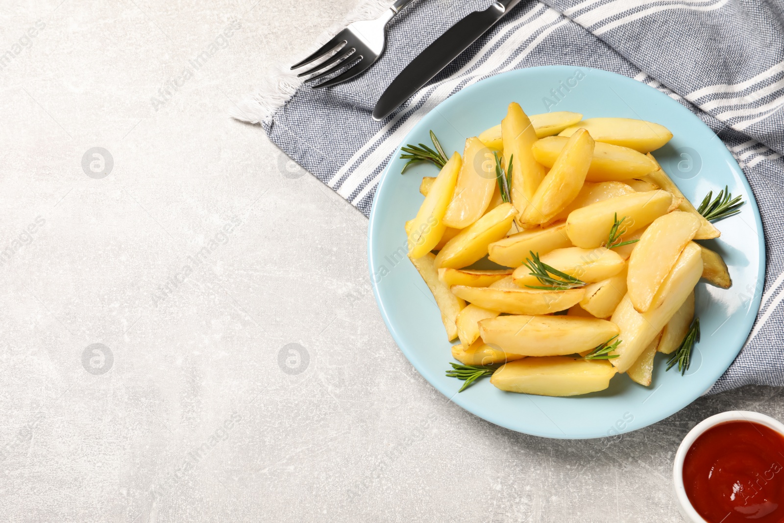 Photo of Plate with tasty baked potato wedges, rosemary and sauce on grey table, flat lay. Space for text