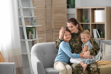 Photo of Woman in military uniform with her children on sofa at home