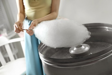 Woman making cotton candy using modern machine indoors, closeup