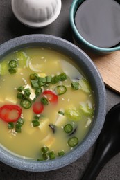 Photo of Bowl of delicious miso soup with tofu served on grey table, flat lay