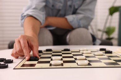 Woman playing checkers at home, closeup view