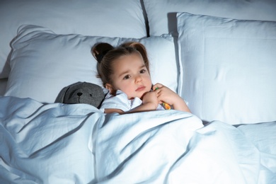 Beautiful little girl with toy in bed at night. Bedtime schedule