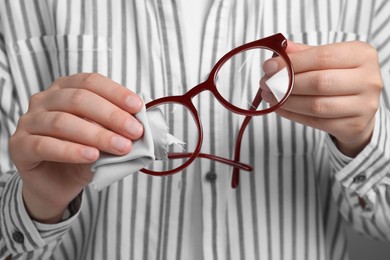 Photo of Woman wiping glasses with microfiber cloth, closeup