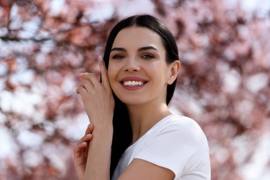 Photo of Pretty young woman near beautiful blossoming trees outdoors. Stylish spring look